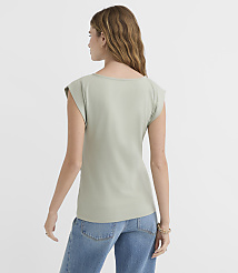 A woman in a light green cap-sleeve shirt and blue jeans stands against a plain white background. carousel Product Image 3