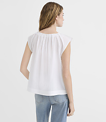 A woman in a white top and jeans stands against a plain white background. carousel Product Image 3