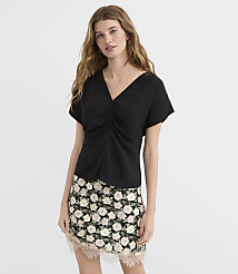 A woman in a black ruched top and floral skirt stands against a plain white background. carousel Product Image 2