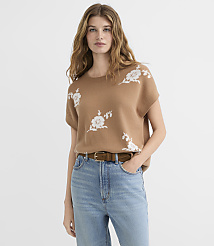 A woman in a tan, floral-patterned sweater and blue jeans stands against a plain white background. carousel Product Image 2