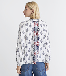 A woman in a patterned white blouse and blue jeans stands against a plain white background. carousel Product Image 4
