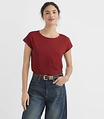 A woman in a red t-shirt and blue jeans stands against a plain white background. carousel Product Image 2