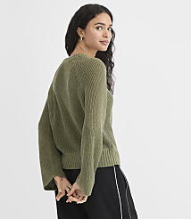 A woman in a green sweater and black pants stands against a plain white background. carousel Product Image 3