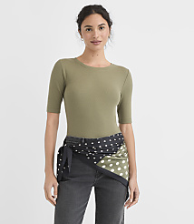 A woman in a green ribbed top and dark jeans stands against a plain white background, with a polka-dotted scarf tied around her waist. carousel Product Image 1