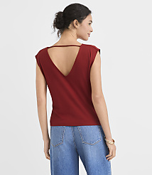 A woman in a maroon v-neck shirt and blue jeans stands against a plain white background. carousel Product Image 3