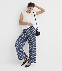 A woman in a white top and patterned blue pants poses against a plain white background. carousel Product Image 1