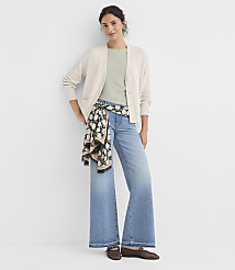 A woman in a cream cardigan and light blue wide-leg jeans stands against a plain white background, with a floral scarf tied around her waist. carousel Product Image 2