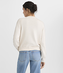 A woman in a cream sweater and blue jeans stands against a plain white background. carousel Product Image 3