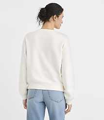A woman in a cream sweatshirt and blue jeans stands with her back to the viewer against a plain white background. carousel Product Image 3