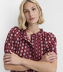A blonde woman with her arms crossed wears a patterned maroon dress against a plain white background. carousel Product Image 2
