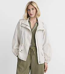 A woman in a light-colored jacket and green striped pants stands against a plain white background. carousel Product Image 1