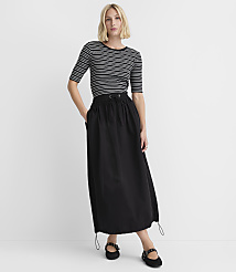 A woman in a striped shirt and a long black skirt stands against a plain white background. carousel Product Image 1