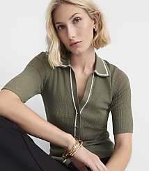 A blonde woman in a green collared shirt and black pants poses against a plain white background. carousel Product Image 1