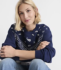 A blonde woman in a navy bandana-print sweatshirt and jeans smiles at the camera against a plain white background. carousel Product Image 2