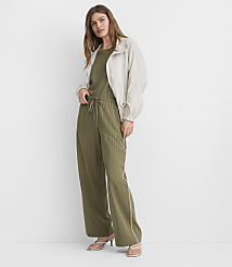 A woman in a light jacket and olive green striped pants stands against a plain white background. carousel Product Image 1