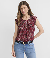 A woman in a patterned maroon blouse and blue jeans stands against a plain white background. carousel Product Image 1