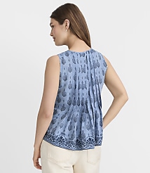 A woman in a patterned blue sleeveless top and cream pants stands against a plain white background. carousel Product Image 3