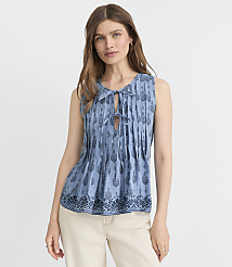 A woman in a blue patterned sleeveless top and cream pants stands against a plain white background. carousel Product Image 1