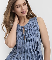 A woman with long brown hair and a blue patterned dress stands against a plain white background. carousel Product Image 2