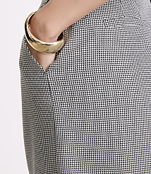 A hand with a gold bracelet rests in the pocket of a houndstooth patterned skirt against a white background. carousel Product Image 4
