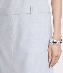 A woman's arm, adorned with a silver bracelet, rests against a pale blue skirt with a visible pocket. carousel Product Image 4