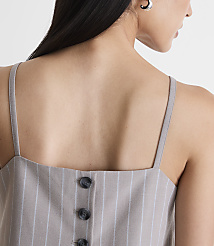 A woman's back is shown in the foreground, wearing a pinstripe top with buttons, against a plain white background. carousel Product Image 4
