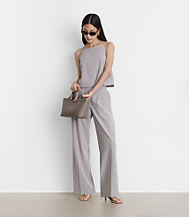 A woman in a pinstripe outfit and sunglasses holds a taupe handbag in front of a plain white background. carousel Product Image 1