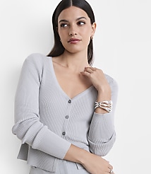 A woman in a light gray ribbed cardigan and bracelet poses against a plain white background. carousel Product Image 2