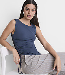 A woman in a blue ruched tank top and striped pants sits on a white chair against a plain white background. carousel Product Image 2