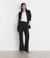 A woman in a black blazer and flared pants stands against a plain white background with a light gray floor in the foreground. carousel Product Image 1