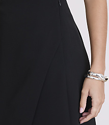 A woman's arm, adorned with a silver bracelet, rests against a black skirt, with a plain, light-colored background. carousel Product Image 4