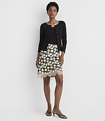 A woman in a black cardigan and floral skirt stands against a plain white background. carousel Product Image 1