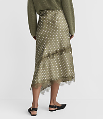 A woman in a polka dot skirt and green sweater stands against a plain white background. carousel Product Image 3