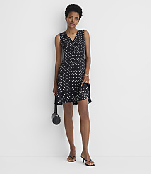 A woman in a polka dot dress and heels stands against a plain white background, holding a small black purse. carousel Product Image 2