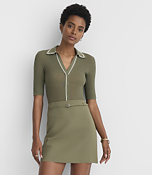 A woman in a green ribbed polo shirt and a matching mini skirt stands against a plain gray background. carousel Product Image 1