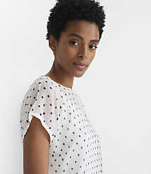 A woman with short, dark hair and a polka-dot shirt is shown against a plain white background. carousel Product Image 2