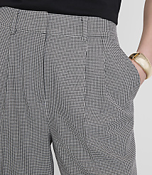 A person's hand, adorned with a gold bracelet, rests in the pocket of houndstooth patterned pants against a plain white background. carousel Product Image 4