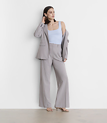 A woman in a light blue tank top and a pinstripe suit stands against a plain white wall. carousel Product Image 1