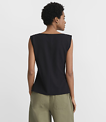 A woman in a black top and green pants stands against a plain white background. carousel Product Image 3