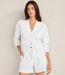 A woman in a white waffle-knit cardigan and shorts stands against a plain, light-colored wall. carousel Product Image 3