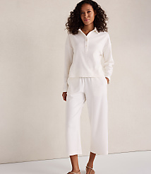 A woman in a white loungewear set stands against a textured, light-colored wall. carousel Product Image 2