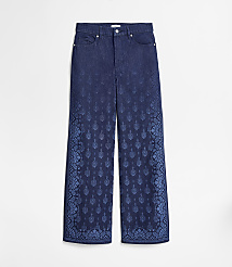 A pair of dark blue wide-leg jeans with a faded, ornate pattern on the lower legs are displayed against a plain white background. carousel Product Image 5