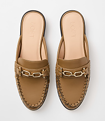 A pair of tan leather mules with gold chain accents and woven detailing are displayed against a plain white background. carousel Product Image 3