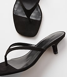 A pair of black suede thong sandals with kitten heels rests on a white surface, with another sandal partially visible in the upper background. carousel Product Image 2