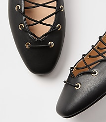 Two black lace-up ballet flats with gold eyelets are arranged on a plain white background. carousel Product Image 2