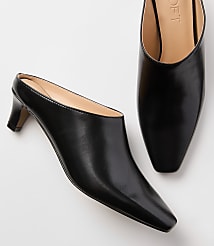 A pair of black leather mules with pointed toes and low heels rests on a plain white background. carousel Product Image 2