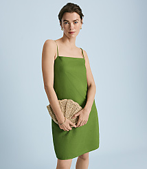 A woman in a green dress holds a woven clutch in front of a light blue background. carousel Product Image 4