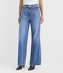 A person stands in wide-leg blue jeans and brown heeled boots against a plain white background. carousel Product Image 2