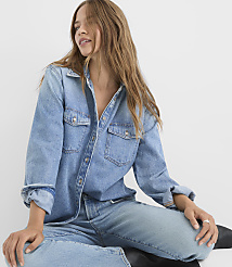 A young woman in a denim shirt and jeans sits against a plain white background. carousel Product Image 4