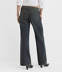 A person wearing dark wash flared jeans and a white top stands against a plain white background. carousel Product Image 3